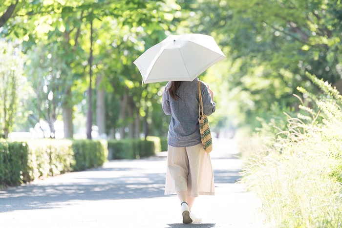 日傘を差して道を歩く女性